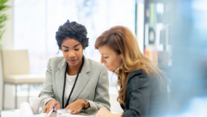 Two HR professionals reviewing workplace complaint documentation before deciding on an investigation