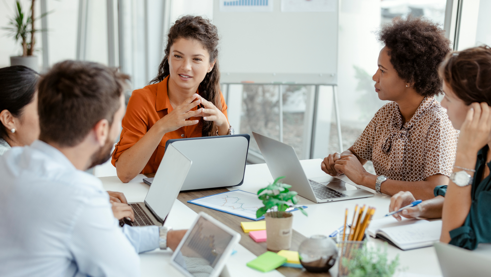 A diverse group of coworkers discussing notes during an office meeting